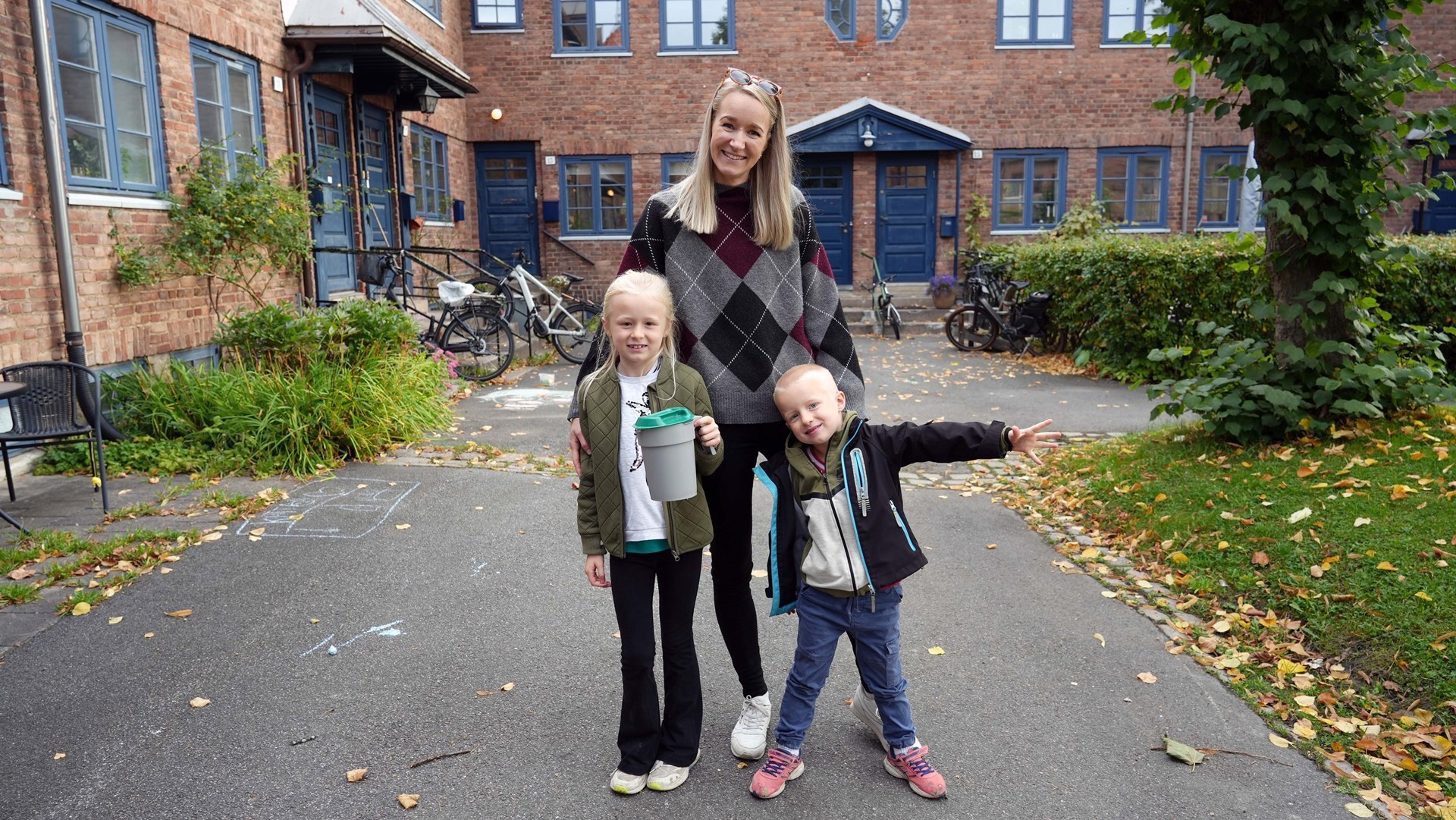 En mor og to barn står med bøsse i et nabolag.
