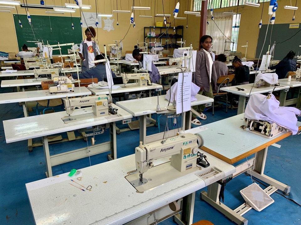 Klasserom med symaskiner og noen elever i bakgrunnen i Etiopia. 