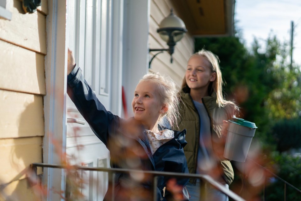 To unge jenter som banker på en dør med bøsse i hånda.