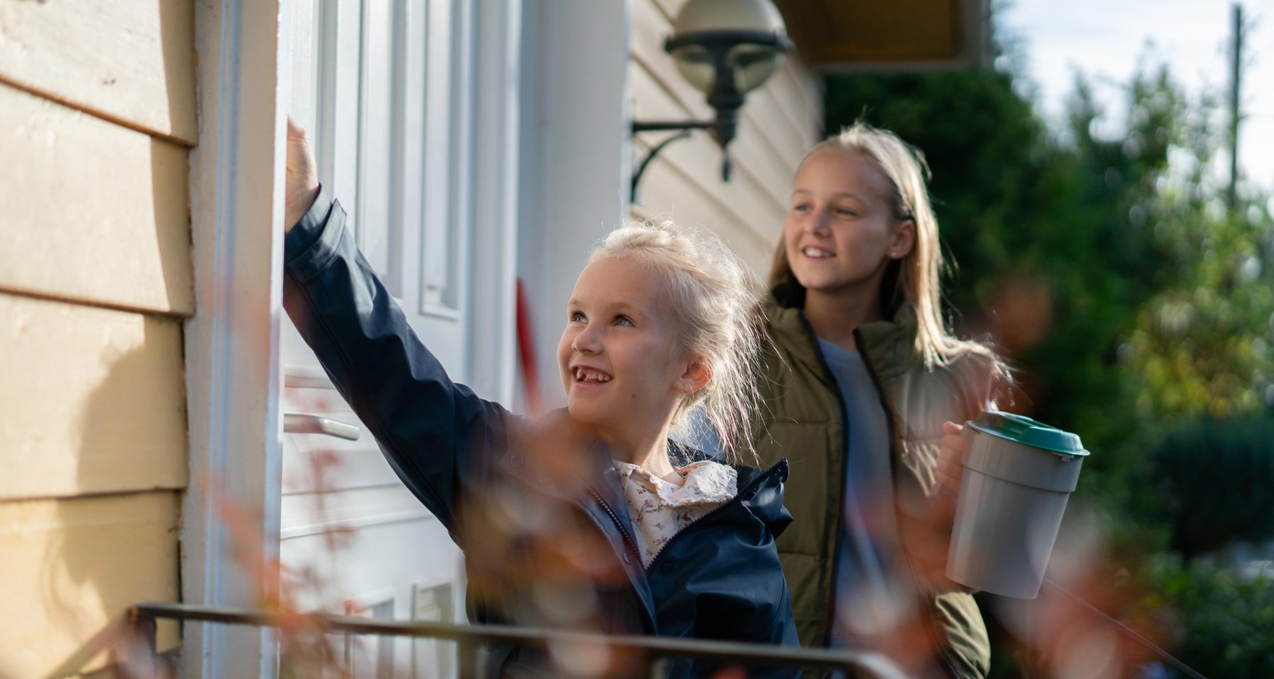 To unge jenter som banker på en dør med bøsse i hånda.